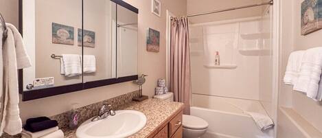 A bathroom with a sink, mirror, vanity, toilet, and shower.