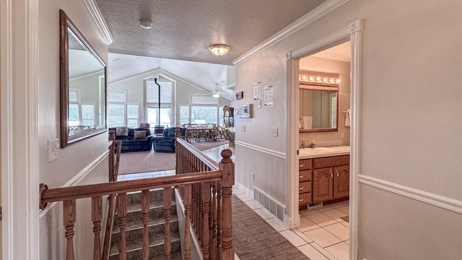 A staircase leading to a living room with a large window, a kitchen area with a vanity, and a ceiling fan.