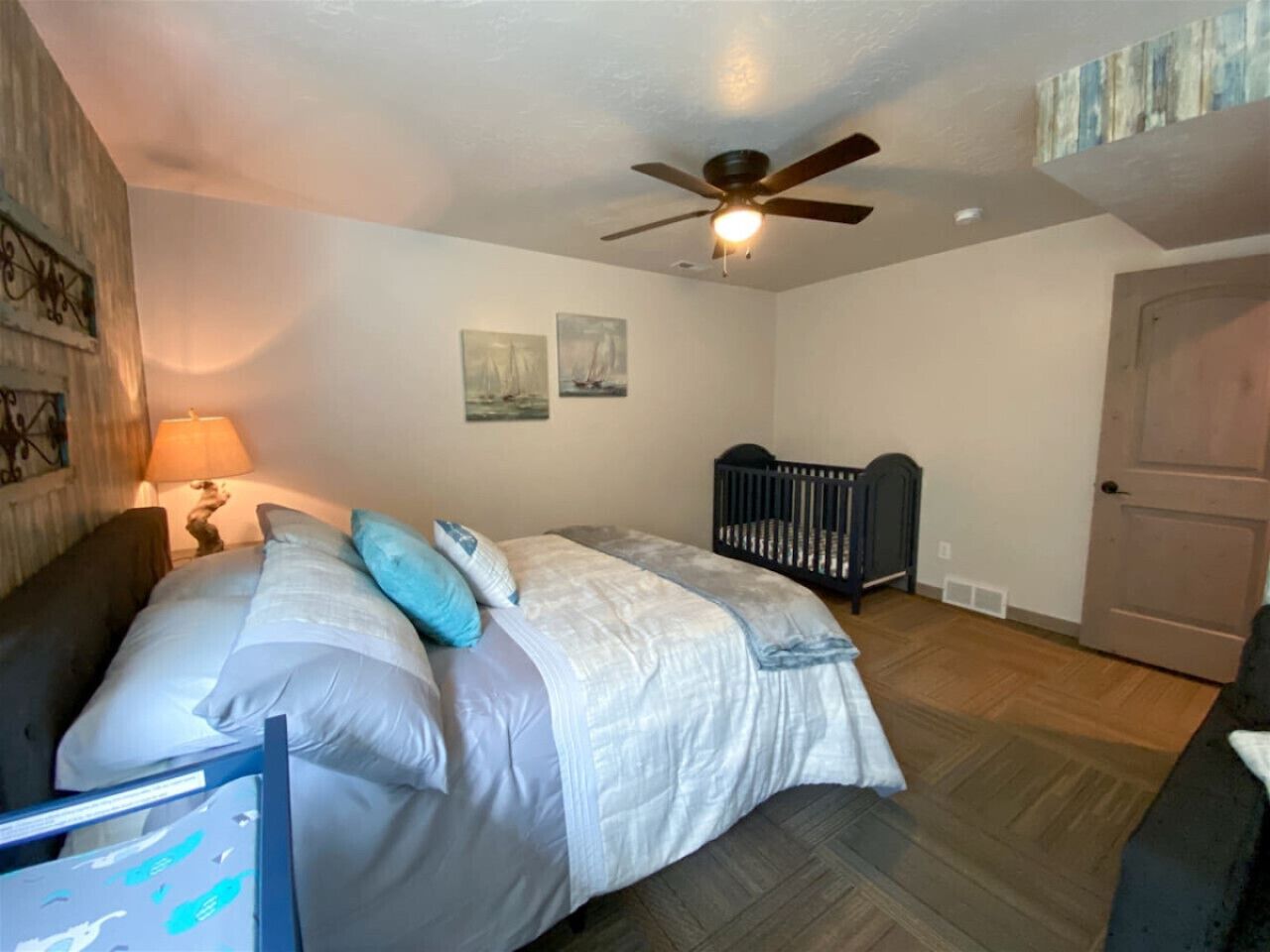 Une chambre à coucher avec un lit, un berceau, un ventilateur de plafond et une porte.
