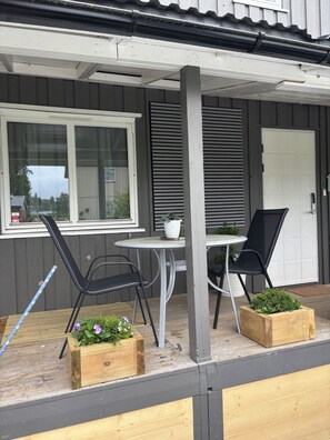 A patio with a table and chairs, a window, and a door.