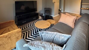 Un salon avec un canapé, un téléviseur, une cheminée et un miroir.