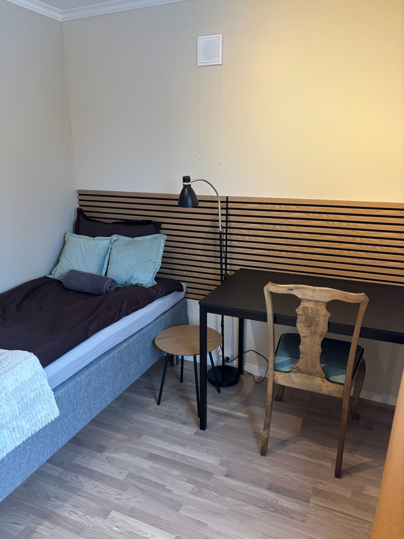 A compact room with a bed, a desk, a chair, and a radiator.