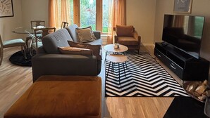 Un salon moderne comprenant un canapé, un fauteuil, un téléviseur et un coin repas avec des chaises et une table.