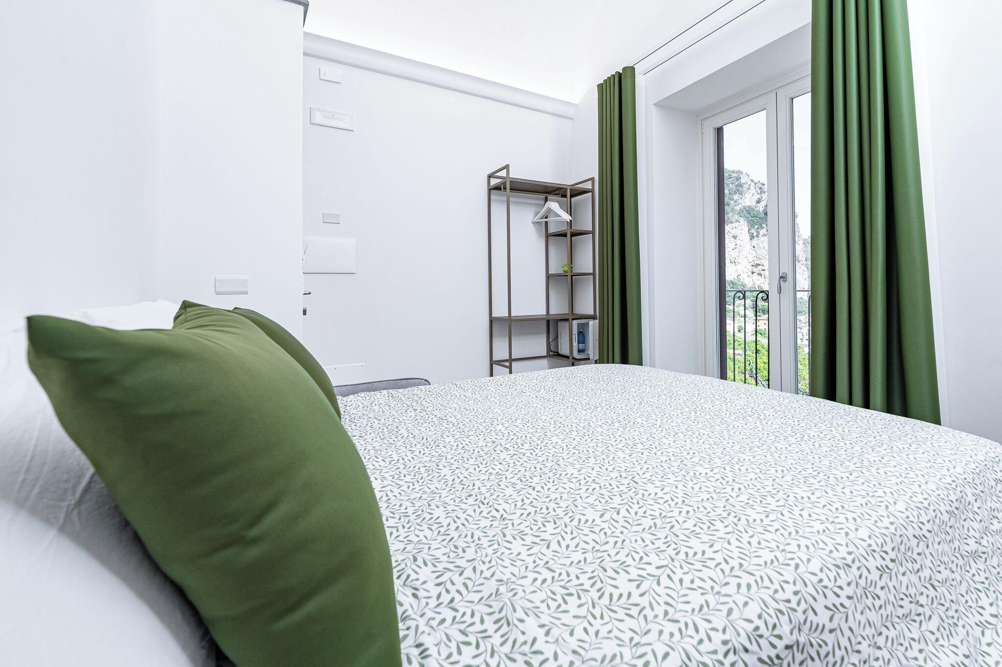 A hotel room with a bed, a wardrobe, and a window with curtains.