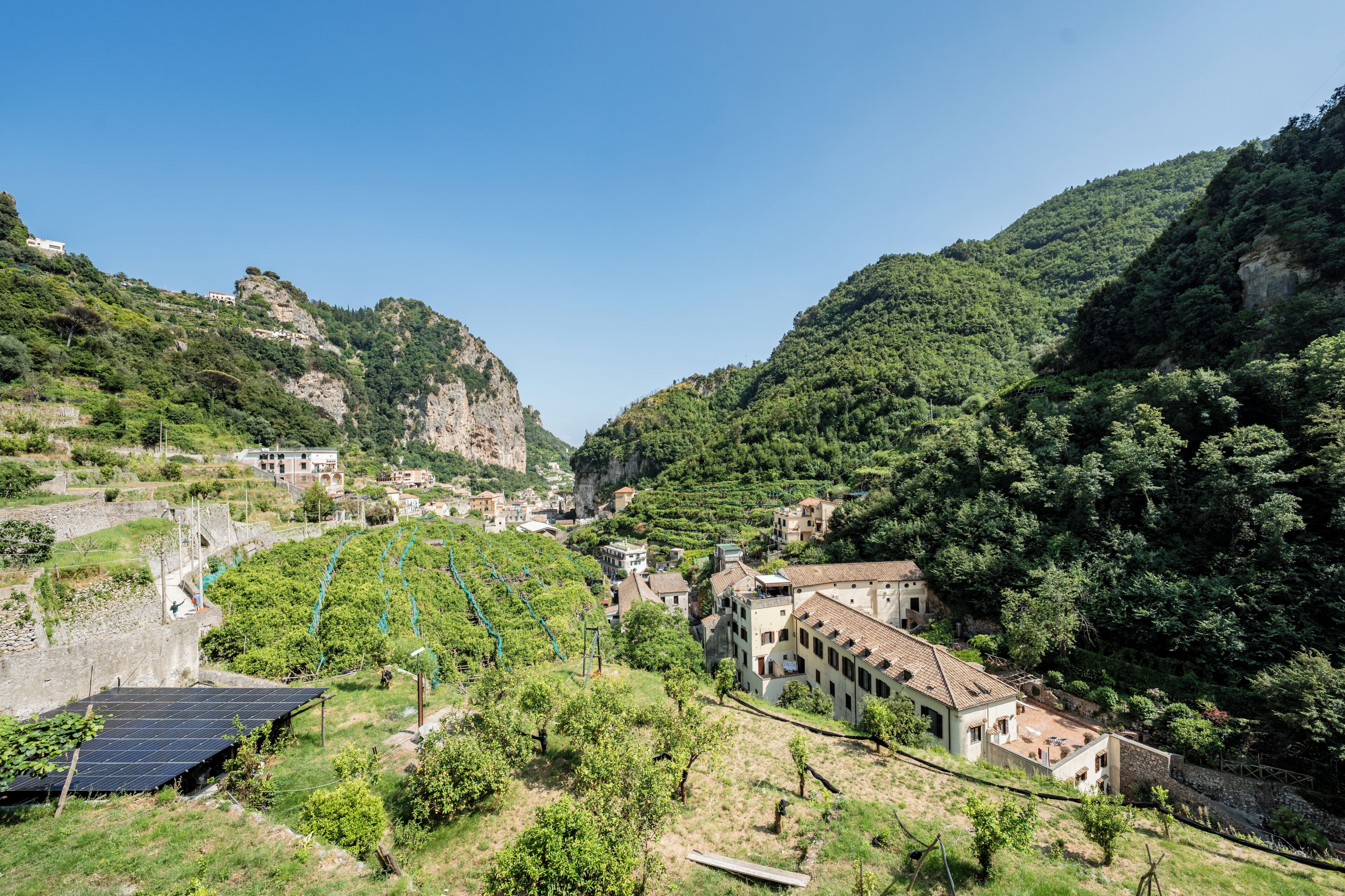 A hillside village with traditional architecture, terraced fields, and a solar panel.