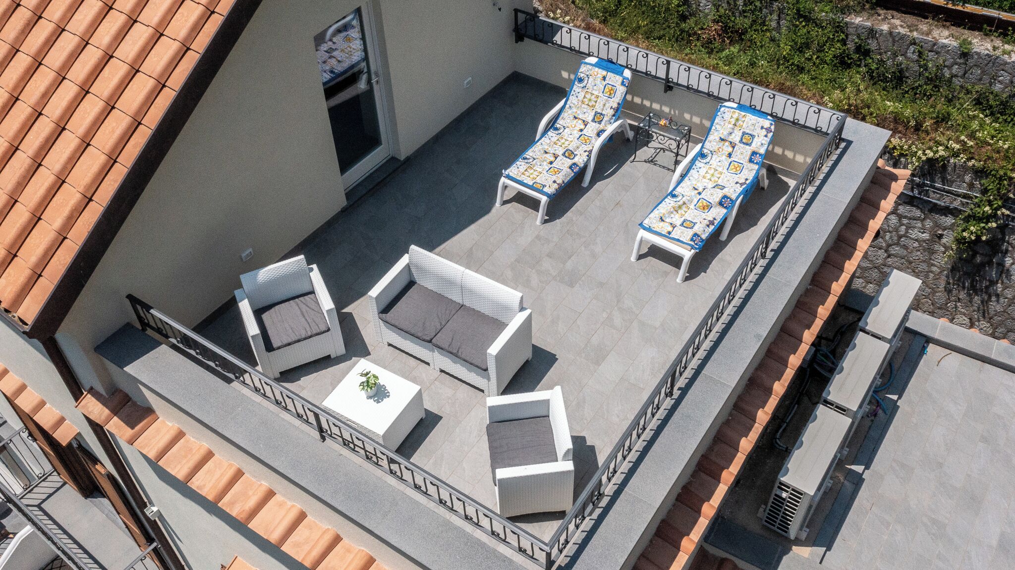 An outdoor patio with two lounge chairs, a sofa, and a small table.
