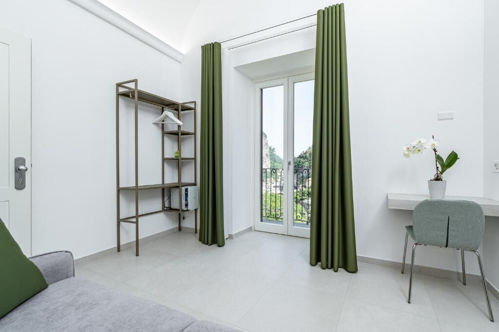 A modern room with a built-in wardrobe, a desk with a chair, and a view through a glass door.