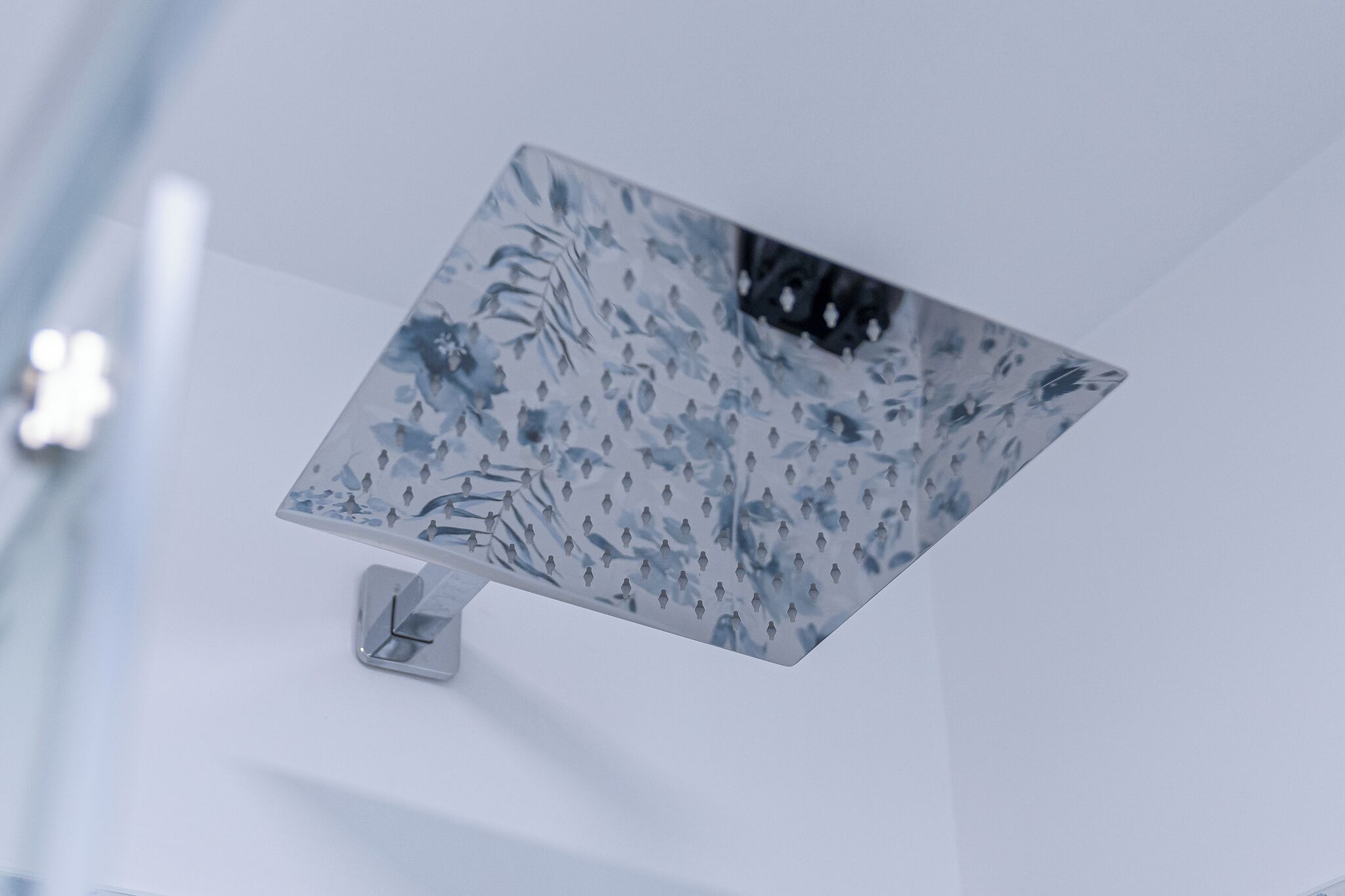 A modern, minimalist room with a geometric patterned ceiling and a sleek, metallic light fixture.