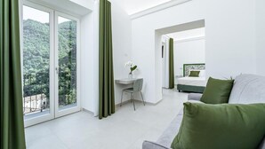 A modern hotel room with a balcony, a desk, a bed, and a sofa. - Villa Zagara (Amalfi)