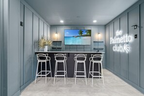 A bar area with a TV screen, bar stools, and a neon sign. - Family-Friendly Home w/ Pool & Arcade Near Beach (North Myrtle Beach)