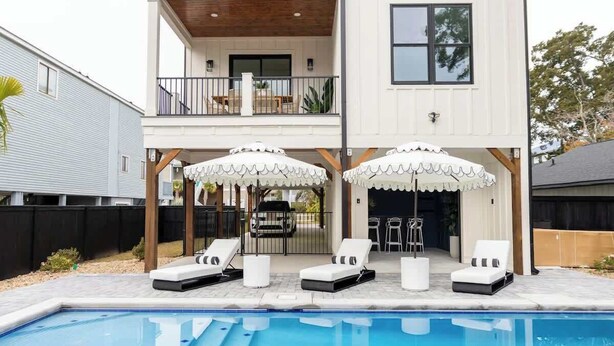 A two-story house with a pool area featuring lounge chairs and umbrellas. - Family-Friendly Home w/ Pool & Arcade Near Beach (North Myrtle Beach)