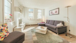 Ein modernes Wohnzimmer mit grauem Sofa, weißem Couchtisch und einer Stehlampe.