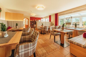 Ein Restaurant mit modernem Interieur, das Holztische und -stühle, einen Weinkeller und einen Ausblick durch große Fenster bietet.