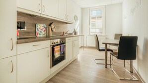 Eine moderne Küche mit Einbauofen, einem Esstisch mit Stühlen und einem Fenster, das für natürliches Licht sorgt.