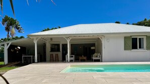 Ett hus med en täckt uteplats, en swimmingpool och en trädgård.