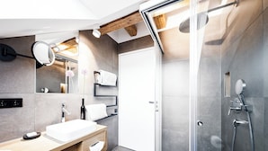 A modern bathroom with a glass shower enclosure, a wooden vanity with a sink, and a mirror with a light fixture. - Stylish apartment in Tiefenbach (Östringen)