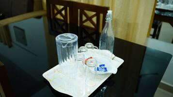 A dining table with a tray containing a bottle, glasses, and condiments.