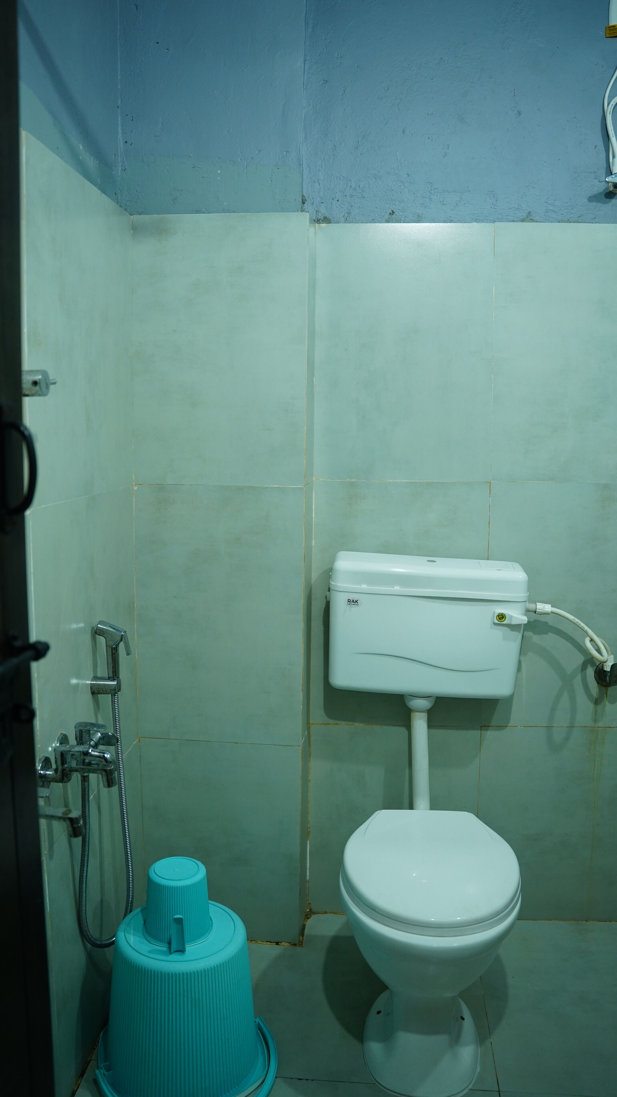 Un baño pequeño y sencillo con inodoro, ducha y calentador de agua.