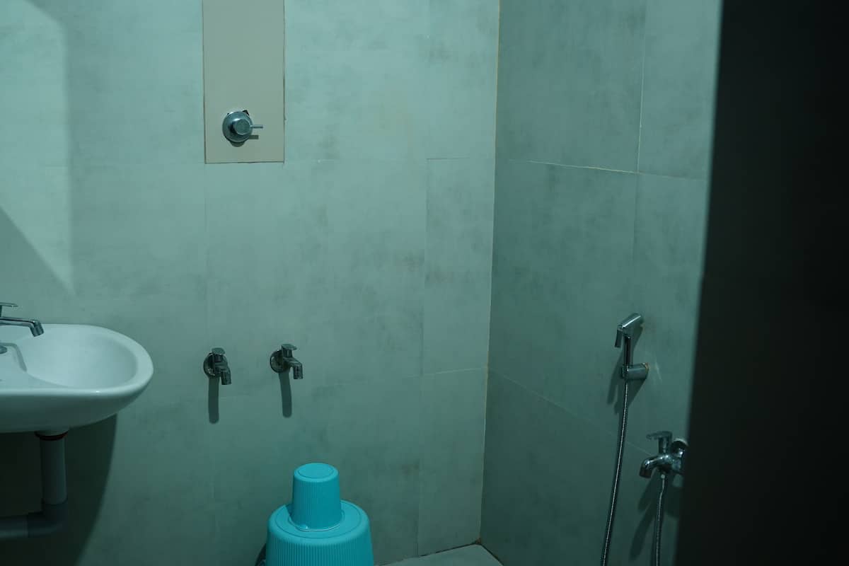 A bathroom with a sink, two faucets, a shower, and a toilet.