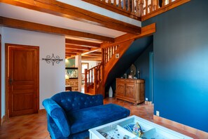 A living room with a blue sofa, wooden beams, a staircase, and a cabinet. - Le Havre de Rhuys - Maison Authentique Familiale (Sarzeau)