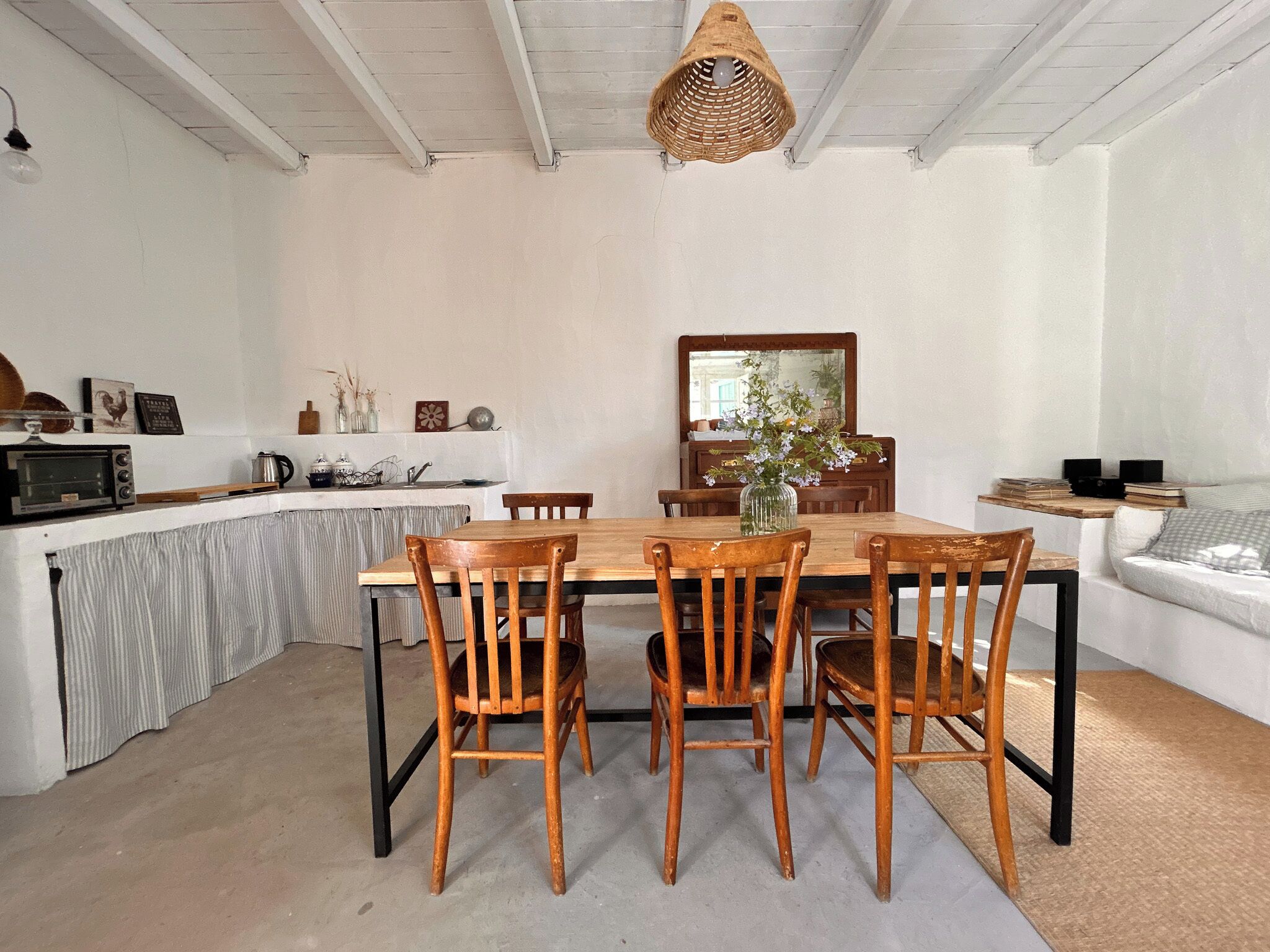 Un coin repas avec une table et des chaises en bois, un luminaire suspendu et un comptoir de cuisine équipé d’appareils électroménagers.