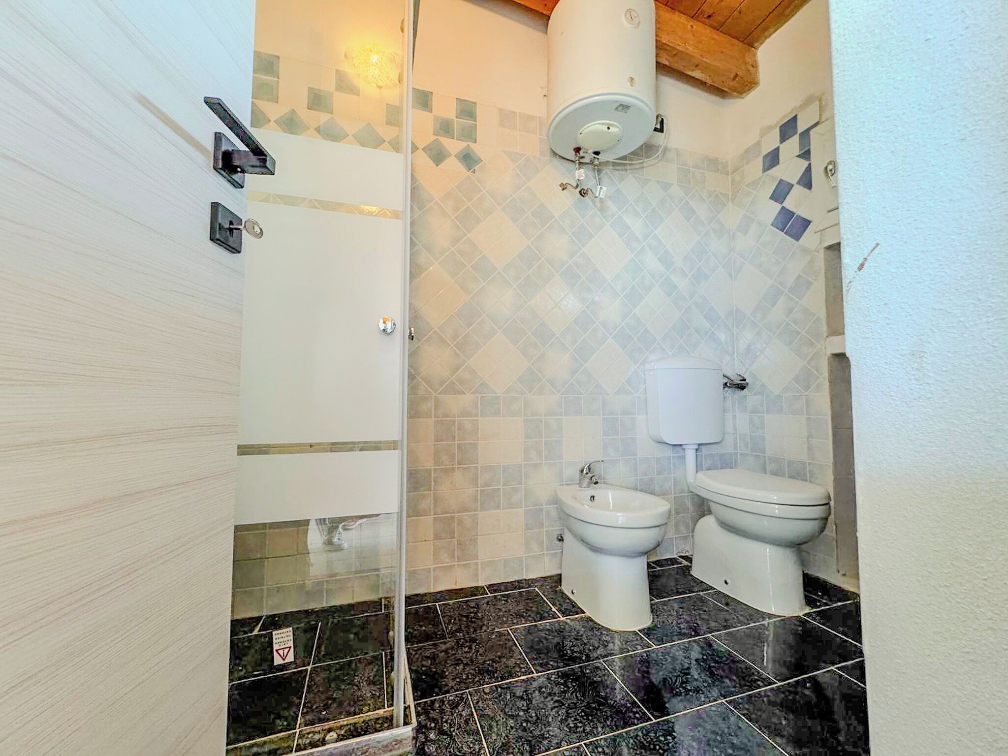 A bathroom with a shower, two toilets, and a toilet paper holder.