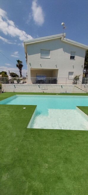 Un edifici modern amb piscina i zona coberta.
