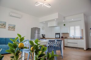 A modern kitchen with white cabinets, a built-in oven, and a stainless steel refrigerator. - Villa Rosy (Butera)