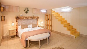 A bedroom with a bed, bedside tables, a bench, a wooden staircase, and a wall-mounted shelf. - Villetta Tra Mari E Monti (San Giovanni Rotondo)