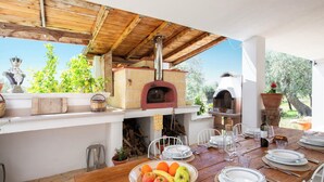 An outdoor dining area with a rustic wooden table set for a meal, surrounded by stone walls and a wooden ceiling. - Villetta Tra Mari E Monti (San Giovanni Rotondo)