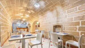 Un espace repas avec des murs en briques, des chaises blanches et des tables.