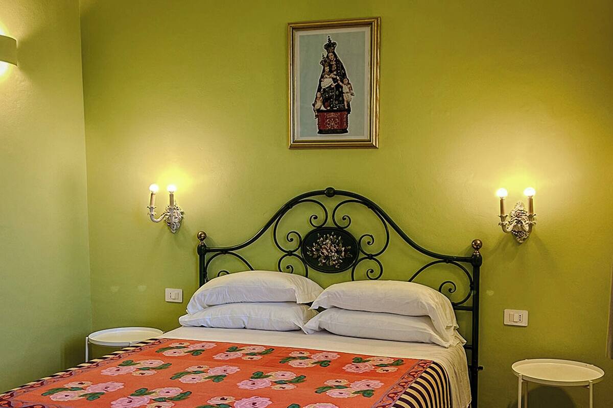 A bed with a floral bedspread, two wall-mounted light fixtures, and a framed picture above the bed.