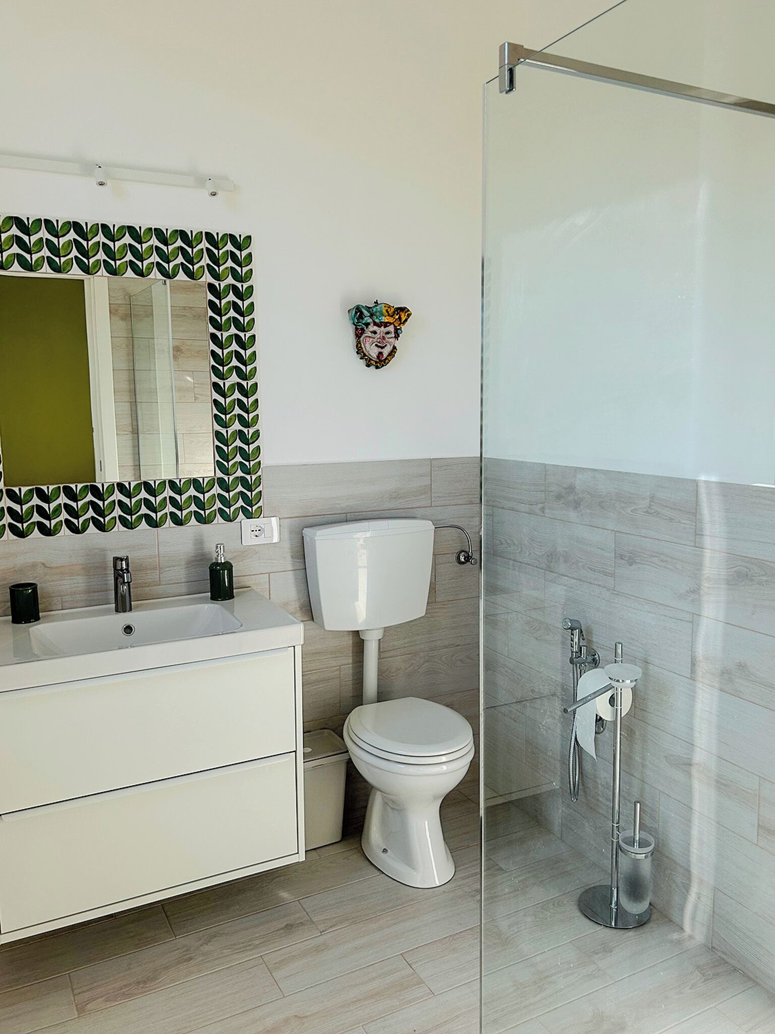 A bathroom with a white sink, mirror, toilet, and shower.