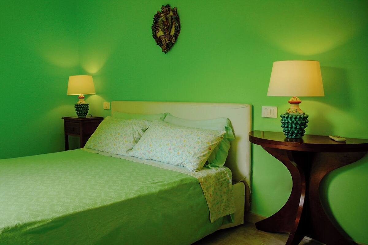 A room with a bed, two nightstands, and a wall-mounted light fixture.