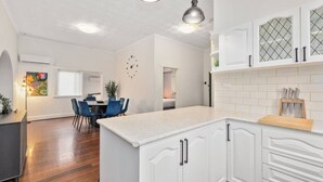 Eine moderne Küche mit weißen Schränken, einer Holz Arbeitsplatte und Pendelleuchten.