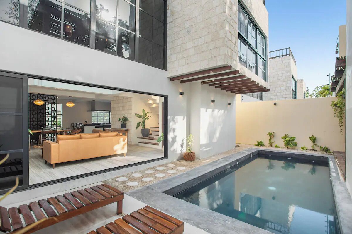 Una casa moderna con piscina, un banco de madera y un sofá en la sala de estar.