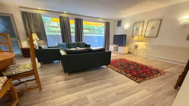 Een moderne woonkamer met een bank, een eettafel en een televisie.