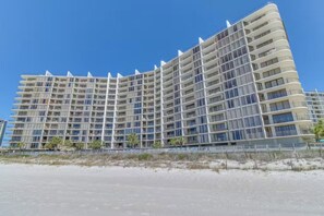 A large, multi-story hotel with a curved facade, located near a sandy beach. - Serenity Shores PCB @ Edgewater - 5th floor, balcony, stunningly updated (Panama City Beach)