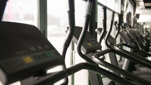 Una hilera de bicicletas estáticas con paneles de control, dispuestas en un gimnasio.