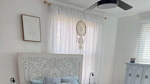 A bedroom with a large bed, a nightstand, a dresser, and a ceiling fan.