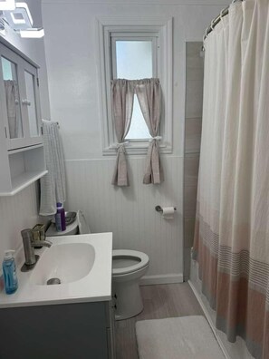 Pieni kylpyhuone, jossa on wc, pesuallas ja ikkuna.