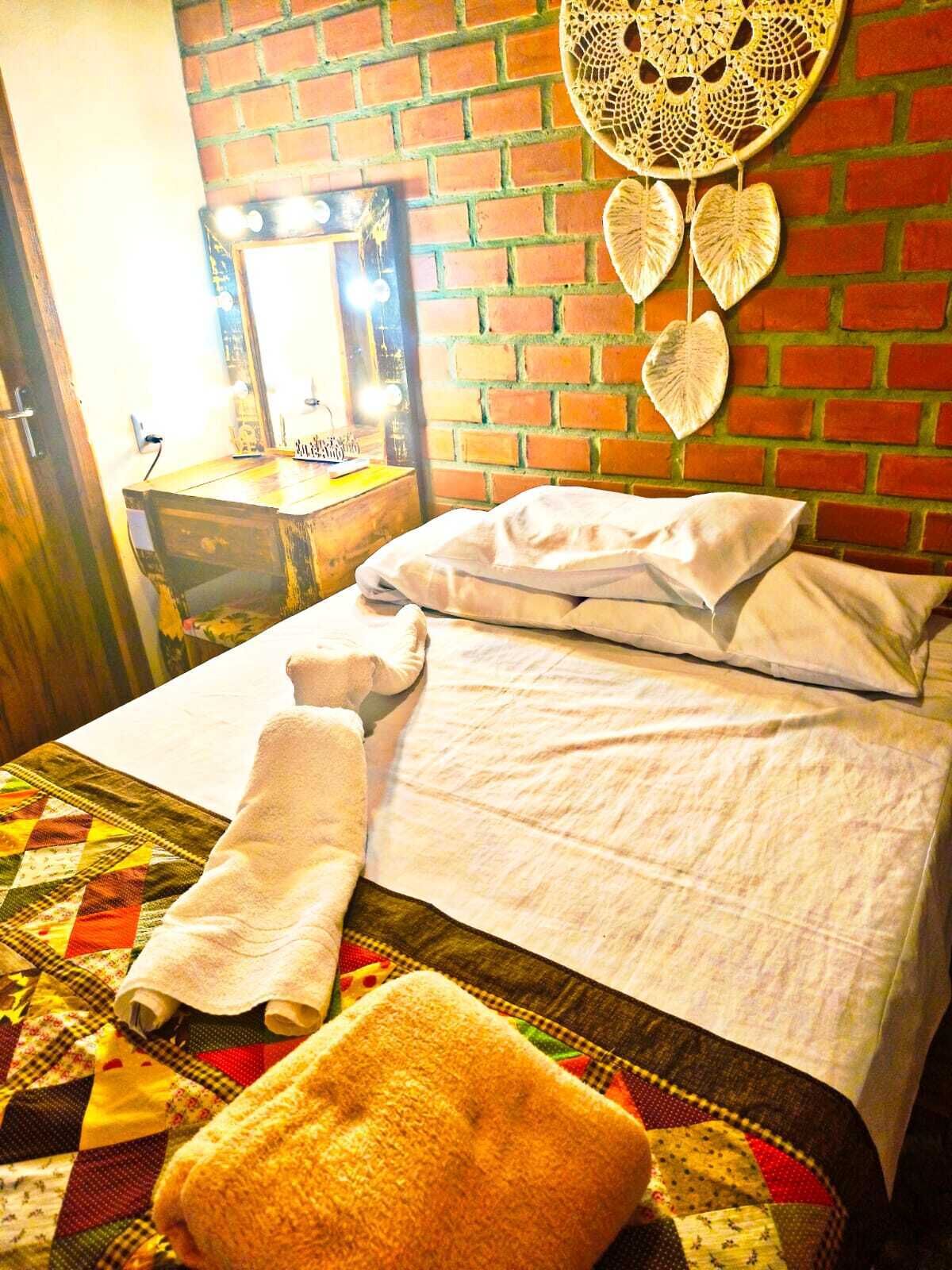 A neatly made bed with a quilt, a bedside table with a lamp, and a wall with a decorative item.
