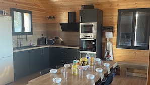 Una cocina compacta con una isla central, electrodomésticos integrados y un comedor con mesa y sillas de madera.