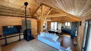 Una cabaña de madera espaciosa con sala de estar que incluye un sofá, televisor y chimenea.
