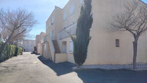 A residential building with a central staircase, a small garden area, and a paved driveway. - Duplex apartment for seaside vacations (LE GRAU D'AGDE)
