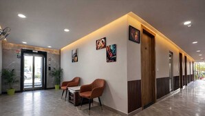 Un hall d’entrée moderne avec un comptoir de réception, deux fauteuils et des œuvres d’art accrochées aux murs.