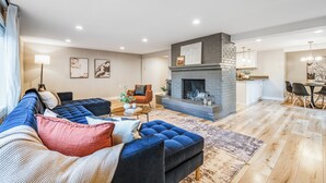 Ein modernes Wohnzimmer mit einem Ecksofa, einem Kamin und einem Essbereich.
