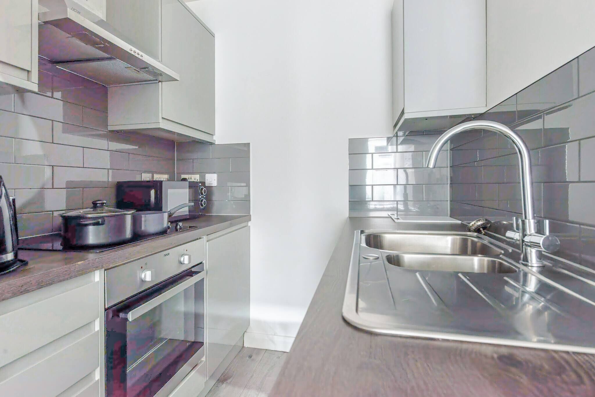 Cocina moderna con electrodomésticos de acero inoxidable, un lavamanos doble y un microondas.