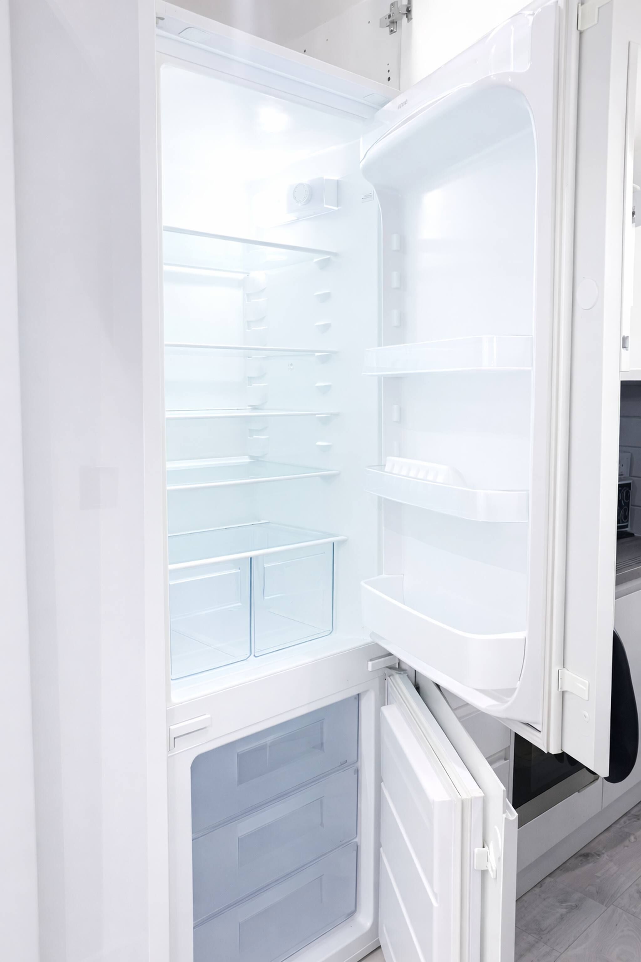 Un refrigerador abierto con múltiples estantes y cajones, que indica un electrodoméstico de cocina moderno.