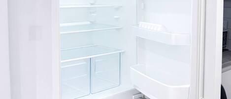 Un refrigerador abierto con múltiples estantes y cajones, que indica un electrodoméstico de cocina moderno.